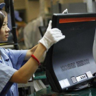 Una mujer trabaja en la línea de producción de Lenovo, en la planta que la empresa tiene en Shanghái.-EUGENE HOSHIKO (AP)