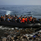 Un migrante afgano salta de una sobresaturada patera al alcanzar la playa en Lesbos (Grecia), el 19 de octubre del 2015.-YANNIS BEHRAKIS