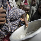 Una mujer con su bebé mientras hace cola para conseguir alimentos en un campamento para los desplazados de Mogadiscio (Somalia)-REUTERS