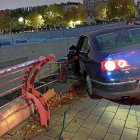 El vehículo Volkswagen empotrado contra una valla que protege el desnivel  del centro comercial.-EL MUNDO