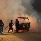 Dos bomberos tratan de apagar un coche incendiado durante los disturbios protagonizados por aficionados al fútbol en El Cairo el pasado 8 de febrero.-Foto: AFP/ STR