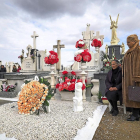 Dos mujeres elevan una oración por sus seres queridos al lado de su tumba.-M.Á. SANTOS (PHOTOGENIC)