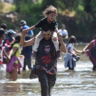 Varios migrantes cruzan el río Suchiate con sus hijos en brazos.-JOHAN ORDONEZ (AFP)