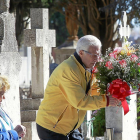Un hombre deposita un centro de flores sobre una de las lápidas en la víspera del Día de Todos los Santos.-J.M.LOSTAU