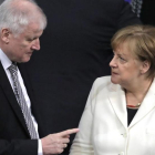 Seehofer (izq) habla con Merkel en el Parlamento alemán, en Berlín, el 14 de marzo.-AP / MARKUS SCHREIBER