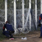 Policías húngaros reparan una agujero en la alambrada de la frontera con Serbia.-AP / MATTHIAS SCHRADER