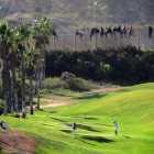 Inmigrantes encaramados en la valla de Melilla, el pasado octubre, mientras varias personas juegan en un campo de golf de la ciudad autónoma.-Foto: AP/ Jose Palazon