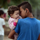 Un chico sostiene en brazos a su hermano pequeño en el campo de refugiados de Kara Tepe, donde algunos fueron trasladados tras un incendio en el de Moria, en Lesbos (Grecia), el 21 de septiembre.-AFP / LOUISA GOULIAMAKI