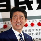 Abe sonríe mientras se dispone a colocar una rosa sobre el nombre de un candidato elegido para la Cámara baja, en la sede de su partido, en Tokio, el 22 de octubre.-REUTERS / KIM KYUNG-HOON