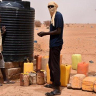 Dos refugiados recogen agua en un tanque en un campo de Níger.-ESMA CAKIR