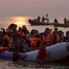 Varios voluntarios ayudan a refugiados a su llegada en un atestado bote neumático a Lesbos, el 20 de marzo.-AP / PETROS GIANNAKOURIS