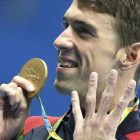 Phelps muestra su medalla señalando los cuatro oros que ha conseguido hasta ahora.-MICHAEL DALDER / REUTERS