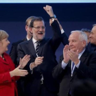 El presidente del Consejo Europeo, Donald Tusk, levanta el brazo de Rajoy en presencia de Angela Merkel y otros dirigentes populares europeos.-AGUSTÍN CATALÁN