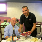 PLATOS CASEROS. José Luis Toral sirve un plato de cecina a Hansen  en el comedor del restaurante Felu, de Portillo (Valladolid).-M. T.