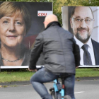 Un ciclista pasa frente a dos carteles electorales de Merkel (izquierda) y Schulz, en Essen, el 14 de septiembre.-AP / MARTIN MEISSNER
