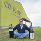 Enrique Concejo posa con dos de sus vinos frente a las instalaciones de su bodega.-