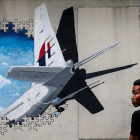 Un joven pasa por delante de un  mural del vuelo MH370 de Malaysia Airlines en Kuala Lumpur el 6 de marzo del 2015.-FAZRY ISMAIL (EFE)