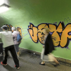 Un grupo de personas pasa  ante un apintada en un pasadizo subterráneo.-E. M.