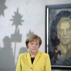 La canciller alemana, Angela Merkel, ante un retrato del excanciller Gerhard Schroeder durante una recepción, hoy, en Berlín.-Foto: EFE