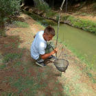 Un joven aficionado a la pesca del cangrejo tras levantar su retel en una acequia regional.-LEONARDO DE LA FUENTE