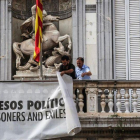 Dos trabajadores de la Generalitat retiran la pancarta que colgaba del Palau.-ÁNGEL GARCÍA