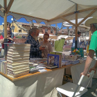 Visitantes ojean un libro en uno de los dieciocho expositores de las librerías locales de Urueña que celebró ayer el X aniversario de la Villa del Libro.-EL MUNDO