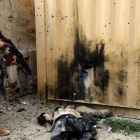 Un soldado afgano junto al cuerpo de un talibán muerto en un ataque en las cercanías de Kandahar.-AFP