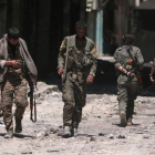 Combatientes de las Fuerzas Democráticas de Siria caminan sobre los escombros de tiendas y edificios dañados por la batalla en la ciudad de Manbij.-RODI SAID (REUTERS)