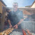 Un hombre cocina en las brasas pincho de lechazo.-MIGUEL ÁNGEL SANTOS