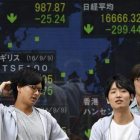 Japoneses en Tokio ante un monitor con la evolución de la bolsa.-EFE / FRANK ROBICHON