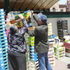 Varias personas buscan fruta en las cajas apiladas en la plaza España al término del mercado diario-J.M.Lostau