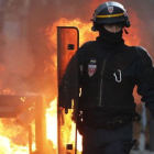 Un policía antidisturbios camina cerca del fuego de una barricada en Toulouse.-EFE / GUILLAUNE HORCAJUELO