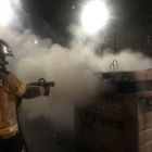 Un bombero extingue el fuego en uno de los contenedores.-TWITTER BOMBEROS