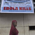Una mujer pasa bajo un anuncio de alerta sobre el virus del Ébola en Freetown (Sierra Leona).-Foto: EFE / TANYA BINDRA