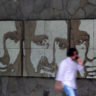Un hombre pasa frente a un muro con los retratos de tres de los seis jesuitas asesinados en El Salvador en 1989, este miércoles.-REUTERS / JOSÉ CABEZAS