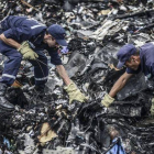 Dos agentes buscan entre los restos del vuelo MH17 de Malaysia Airlines.-AFP / BULENT KILIC