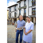 Quelín Rodrigo, con la típica olla podrida, y la cocinera Ángela Marrón, en la Plaza Doña Urraca de Covarrubias, ante Casa Galín.-ARGICOMUNICACIÓN