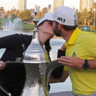 Sergio García besa a su novia, Angela Ankins, junto al trofeo del Omega Dubai Desert Classic.-AFP / KARIM SAHIB