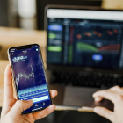 Una persona revisa tanto en su ordenador con en su teléfono móvil una serie de datos. / EL MUNDO
