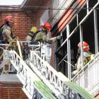Intervención de los bomberos con una escala en el piso incendiado. | J.M. LOSTAU