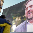 Marta Rovira se abraza a la también candidata Carme Forcadell bajo la mirada de Oriol Junqueras desde la pantalla, en el acto central en el Born.-JORDI COTRINA