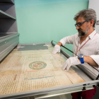 A la izquierda, imagen del documento más antiguo que se conserva. Arriba, el director del Archivo Municipal manipulando un pergamino medieval.-PABLO REQUEJO