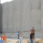 Niños palestinos de camino a la escuela, junto al muro construido por Israel cerca de Qalqilya (Cisjordania).-AP / MOHAMMED AZBA