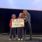 Dos alumnas del colegio entregan el cheque a Carolina Martínez .-E.M.