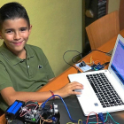 El joven vallisoletano Antonio García posa con un ordenador portatil y un robot.-EL MUNDO