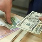 Euros y dólares en las manos.-Foto: ARCHIVO/ AFP