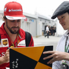 Fernando Alonso firma un autógrafo a un fan en el circuito de Suzuka.-Foto: AFP / TOSHIFUMI KITAMURA