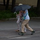 Archivo - Dos personas se protegen de la lluvia con un paraguas.