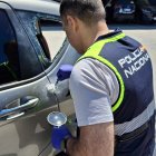 Un agente de la Policía Nacional junto a uno de los vehículos