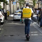 Dos usuarios de patinete eléctrico circulan por  una calzada.